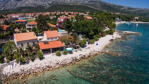 A coastal property with a clear view of the sea, a rocky shoreline, and a residential area with houses.