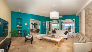 A spacious living area with a teal accent wall, a stone feature wall, and a view through an arched doorway to the outdoors.