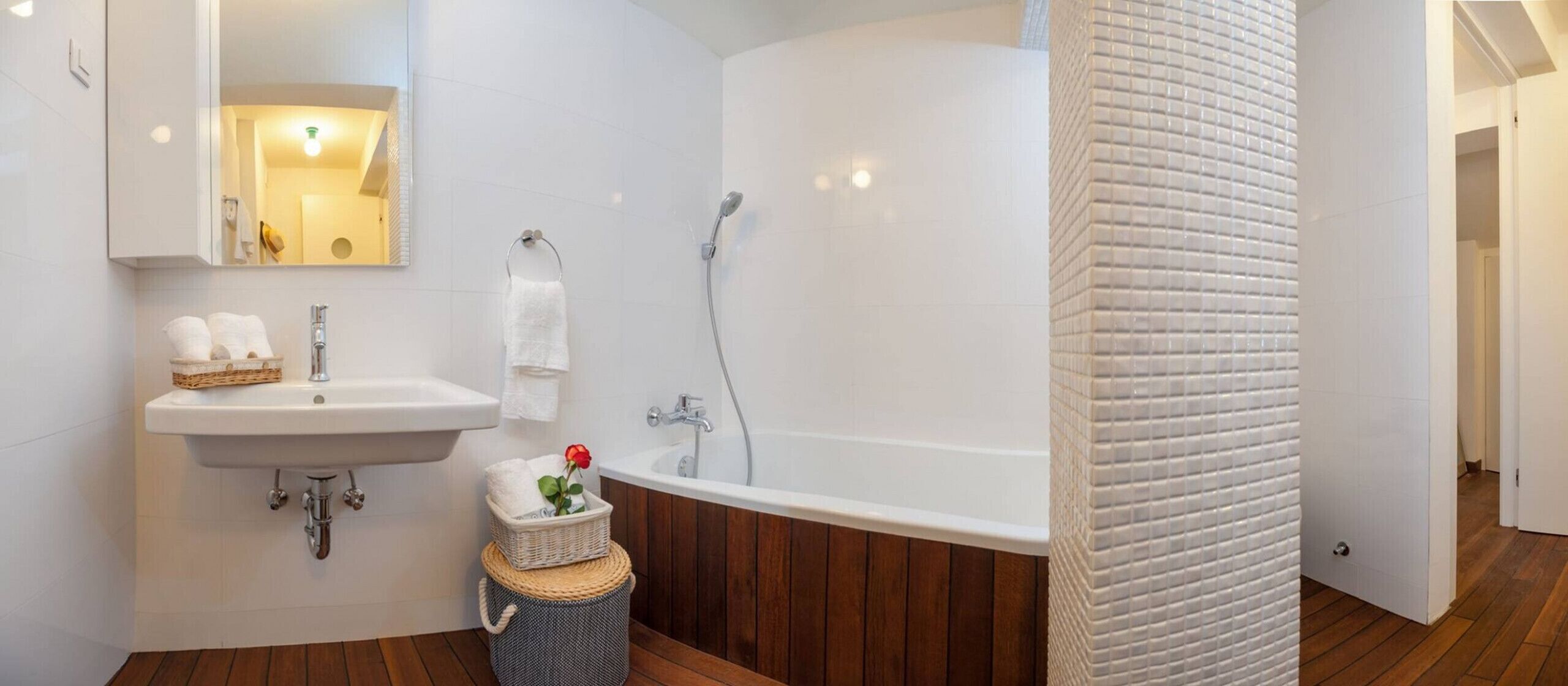 A bathroom with a sink, mirror, and bathtub.