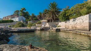 A coastal area with a clear water body, stone walls, and residential buildings. - Luxury Seafront Villa Mare Orebic with Pool (Orebic)