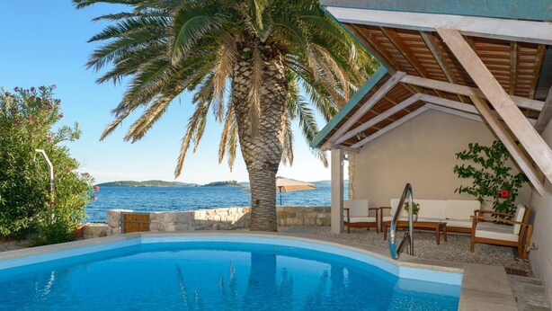 A swimming pool with a view of the sea, a palm tree, and a covered seating area. - Luxury Seafront Villa Mare Orebic with Pool (Orebic)