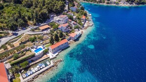 An aerial view of a coastal town with a clear blue sea, a marina with boats, and buildings with red roofs. - Luxury Seafront Villa Gabriela with Pool And Gym (Korcula)