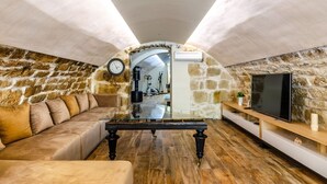 A cozy living room with a stone wall, a sofa, a coffee table, and a TV. - Luxury Seafront Villa Gabriela with Pool And Gym (Korcula)