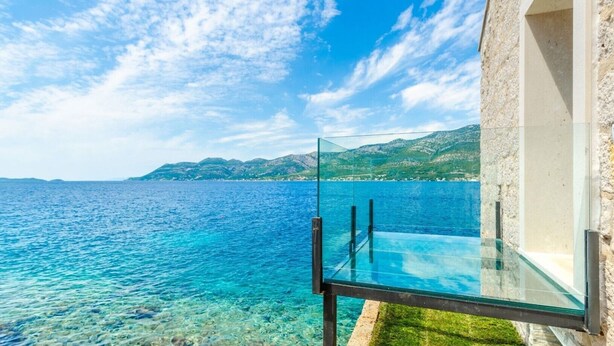 A glass infinity pool overlooking a clear blue sea with a mountainous backdrop. - Luxury Seafront Villa Gabriela with Pool And Gym (Korcula)