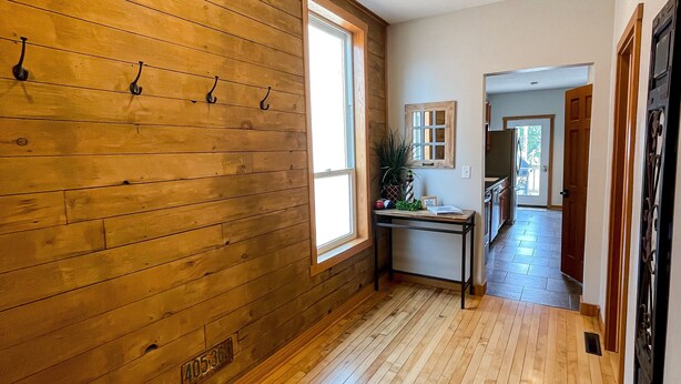 A wooden-paneled hallway with a window, a table with items, and a door leading to another room. - Lakeview Loft (Kewaunee)