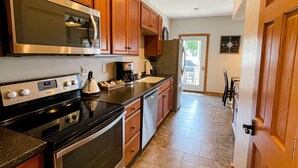 A kitchen with wooden cabinets, stainless steel appliances, and a tiled floor. - Lakeview Loft (Kewaunee)