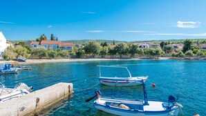 A coastal village with boats docked at a pier, houses along the shore, and clear blue skies. - Luxury Seafront Villa Casa Mare Brač Heated Pool (Supetar)