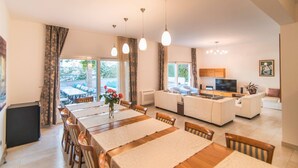 A spacious living area with a dining table, sofas, a TV, and a kitchen area. - Luxury Seafront Villa Casa Mare Brač Heated Pool (Supetar)