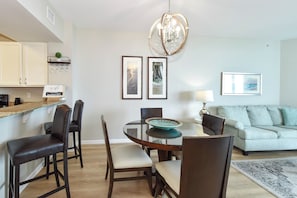 Un comedor con una mesa redonda, sillas, una lámpara de araña y cuadros en la pared.