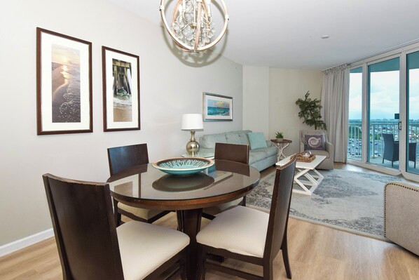 A dining area with a round table, chairs, and a bowl. There is a sofa and a plant in the background. - Tranquil Condo w/ Free Beach Shuttle & Close Dining in Central Destin! ππ¬π΄ (Destin)