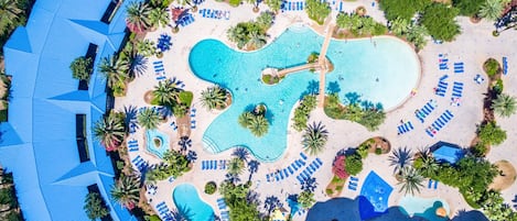 Eine Vogelperspektive eines Resorts mit mehreren Schwimmbecken, Liegestühlen und Palmen.
