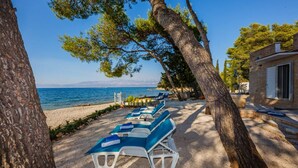 Un cadre idyllique au bord de la plage, avec des chaises longues, un bâtiment et une vue sur la mer.
