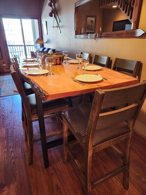 Un coin repas avec une table en bois dressée pour six personnes, entourée de chaises en bois.