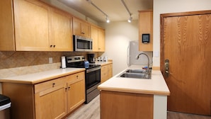 A kitchen with wooden cabinets, a stainless steel microwave, a built-in oven, a sink, and a refrigerator. - Newly Renovated ski-in/ski-out condo at Copper Mountain (Frisco)