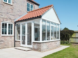 A conservatory with a tiled roof, brick walls, and large glass doors. - 4 bedroom accommodation in Sedgeford (Sedgeford)