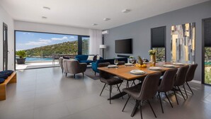 Un espace repas moderne avec une grande table, des chaises et une vue sur la mer.