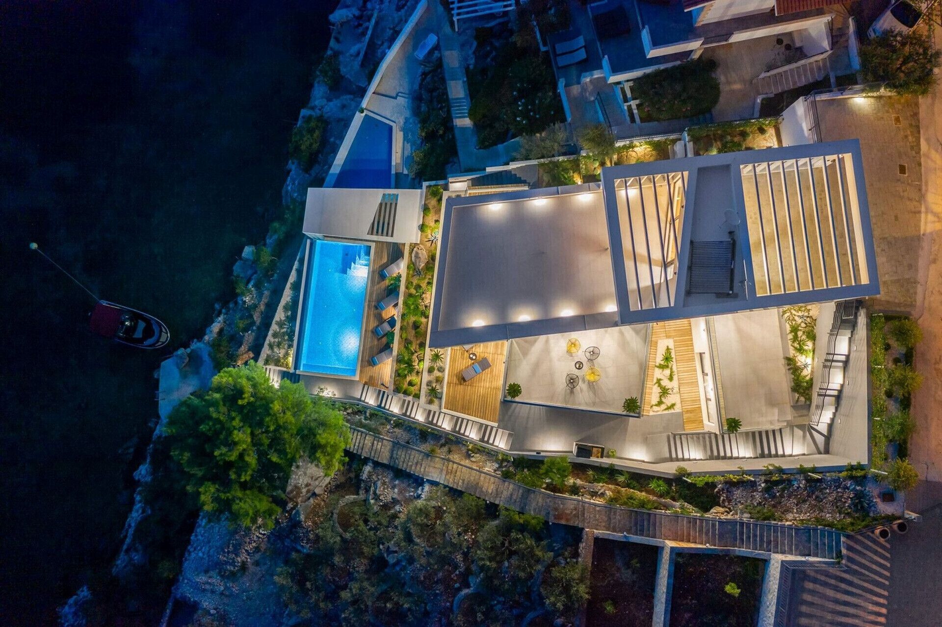 Vue aérienne d’un hôtel moderne doté d’une piscine, d’un espace de détente extérieur et offrant une vue sur la mer.