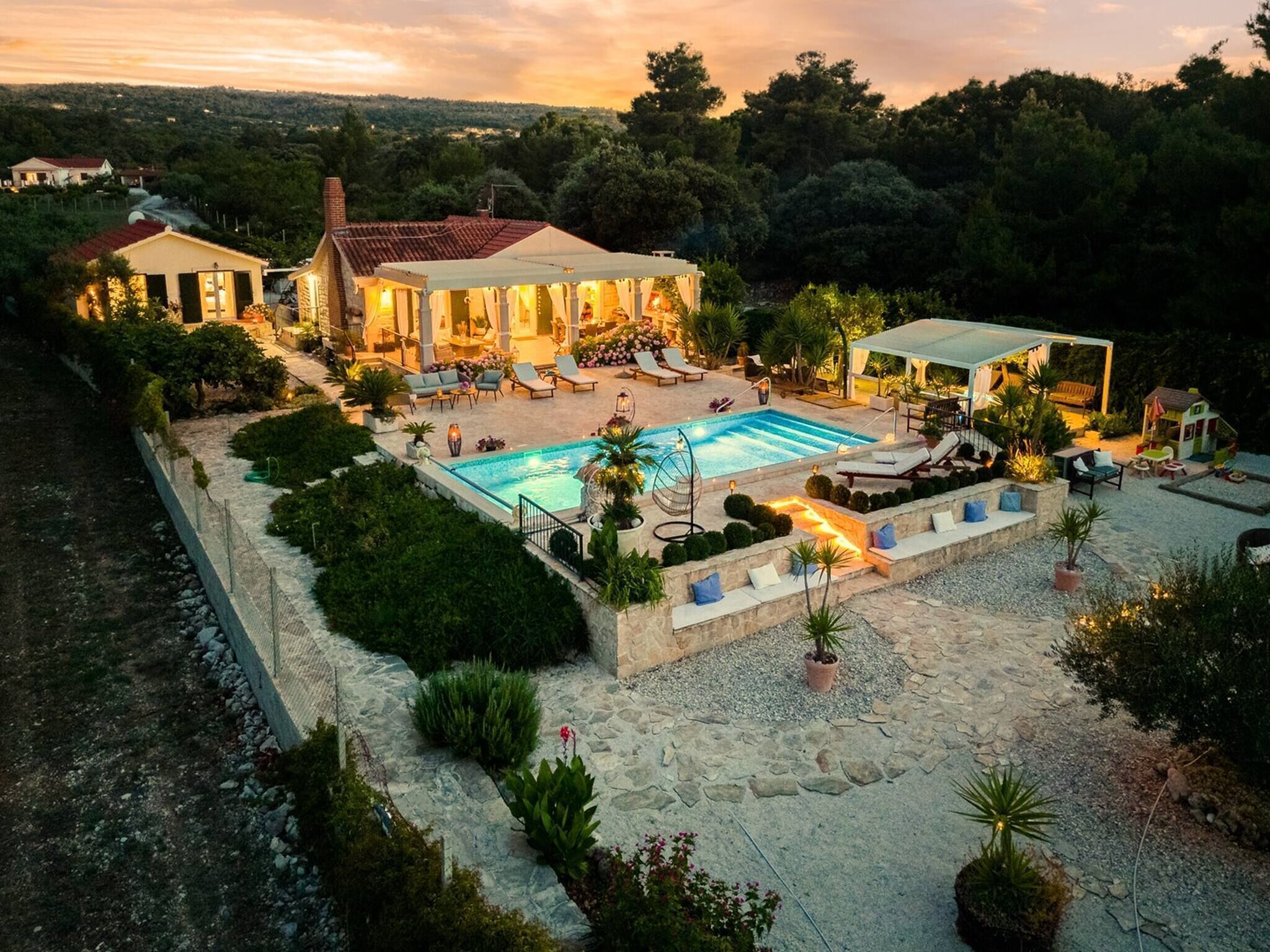A villa with a swimming pool, outdoor seating, and a garden.