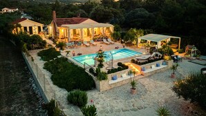 Una villa con piscina, mobiliario exterior y jardín.