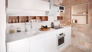 A modern kitchen with white cabinets, a built-in oven, a sink, and a microwave.