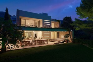 A modern two-story house with a dining area, a living room, and a large patio.