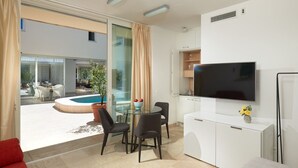 A modern living room with a glass door leading to a pool, a flat-screen TV, and a dining area with chairs. - Luxury Beachfront Villa Castello Bol with Pool (Bol)
