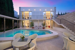Une maison moderne à deux étages dotée d’une piscine, d’un espace salon extérieur et d’un escalier.