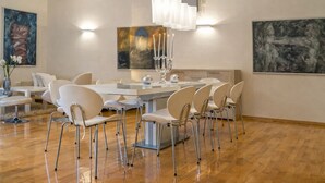 Une salle à manger moderne avec une table centrale, des chaises et un lustre.