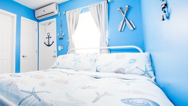 A bedroom with a bed, white walls, and blue accents.