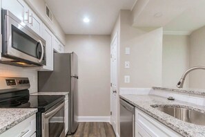 A kitchen with a microwave, stove, refrigerator, and granite countertops. - Sunny Renovated 2BR Condo · Pool · Near DC (West Springfield)