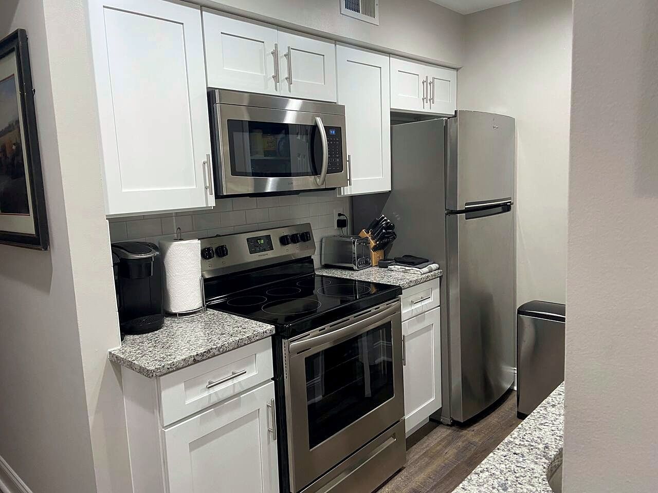 A modern kitchen with white cabinets, stainless steel appliances, and granite countertops.