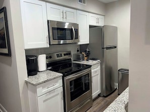 A modern kitchen with white cabinets, stainless steel appliances, and granite countertops.