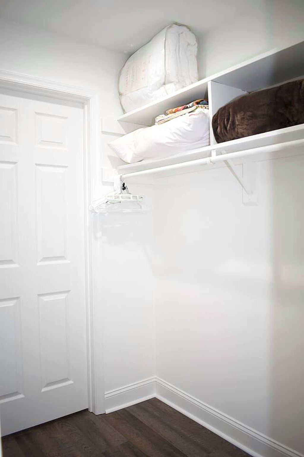 Une porte blanche, un mur blanc et une étagère blanche sur laquelle repose un objet marron.