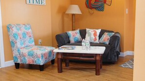 Una sala de estar con sofá, sillón, mesa de centro y un cuadro decorativo con peces.