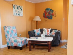 A living room with a sofa, armchair, coffee table, and decorative fish wall art.