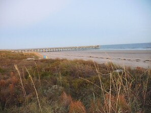 Une plage avec une jetée qui s’avance dans l’eau.