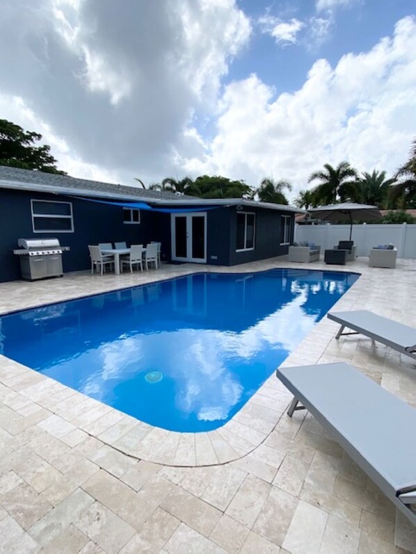 A swimming pool with lounge chairs, a barbecue grill, and a covered patio area. - Family-Friendly 4BR with Pool & Game Room, 5 Mins to Beach! (Deerfield Beach)