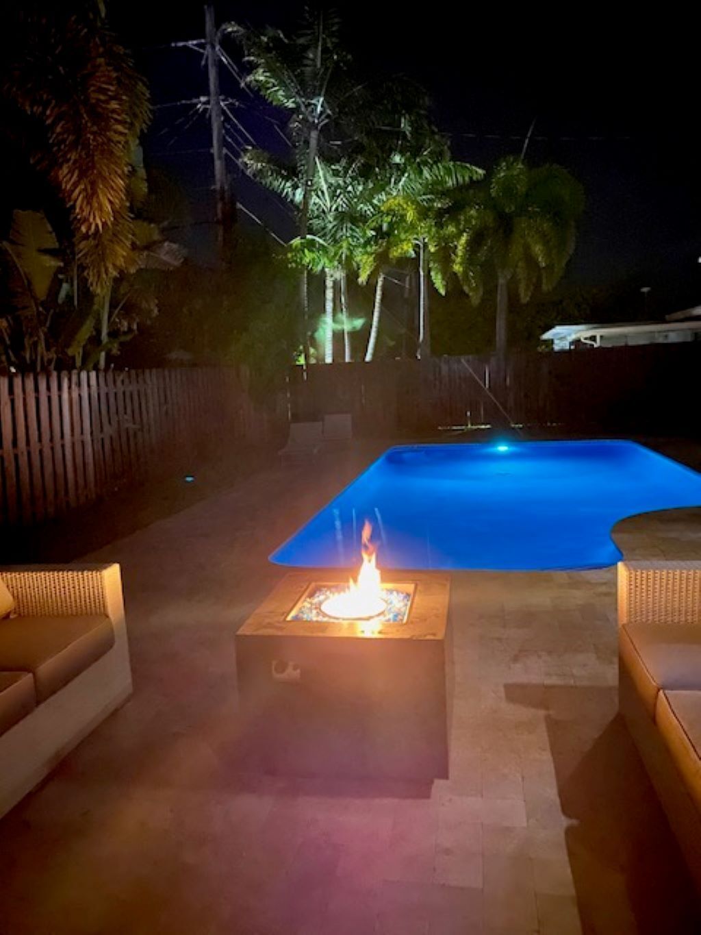 A pool area with a fire feature and outdoor furniture.