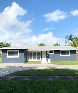 A single-story house with a grey exterior, a front door, and a small porch.