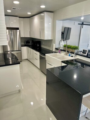 A modern kitchen with stainless steel appliances, white cabinetry, and a black countertop. - Family-Friendly 4BR with Pool & Game Room, 5 Mins to Beach! (Deerfield Beach)