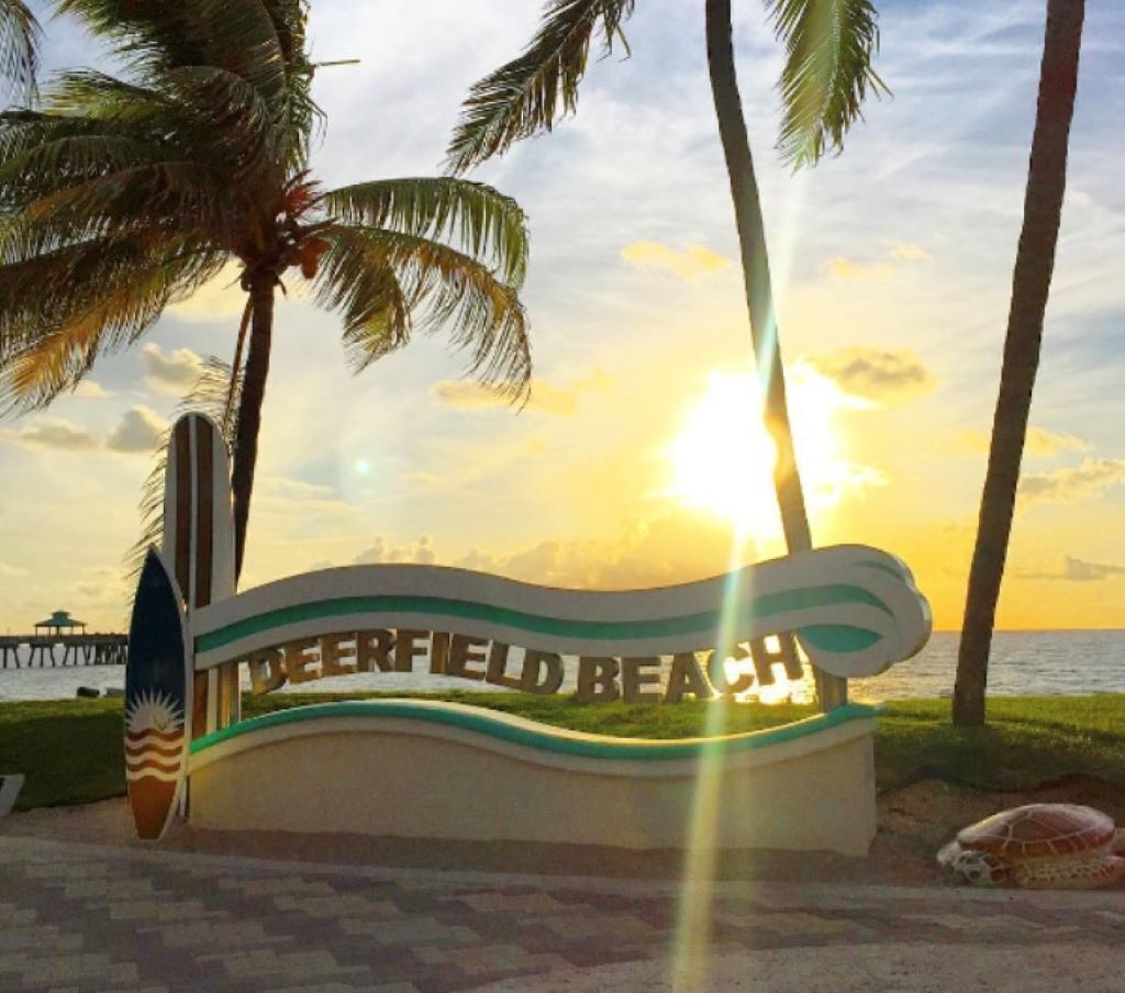 A beach sign with the text "Deerfield Beach" and a surfboard.
