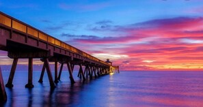 A pier extending into a body of water during sunset.