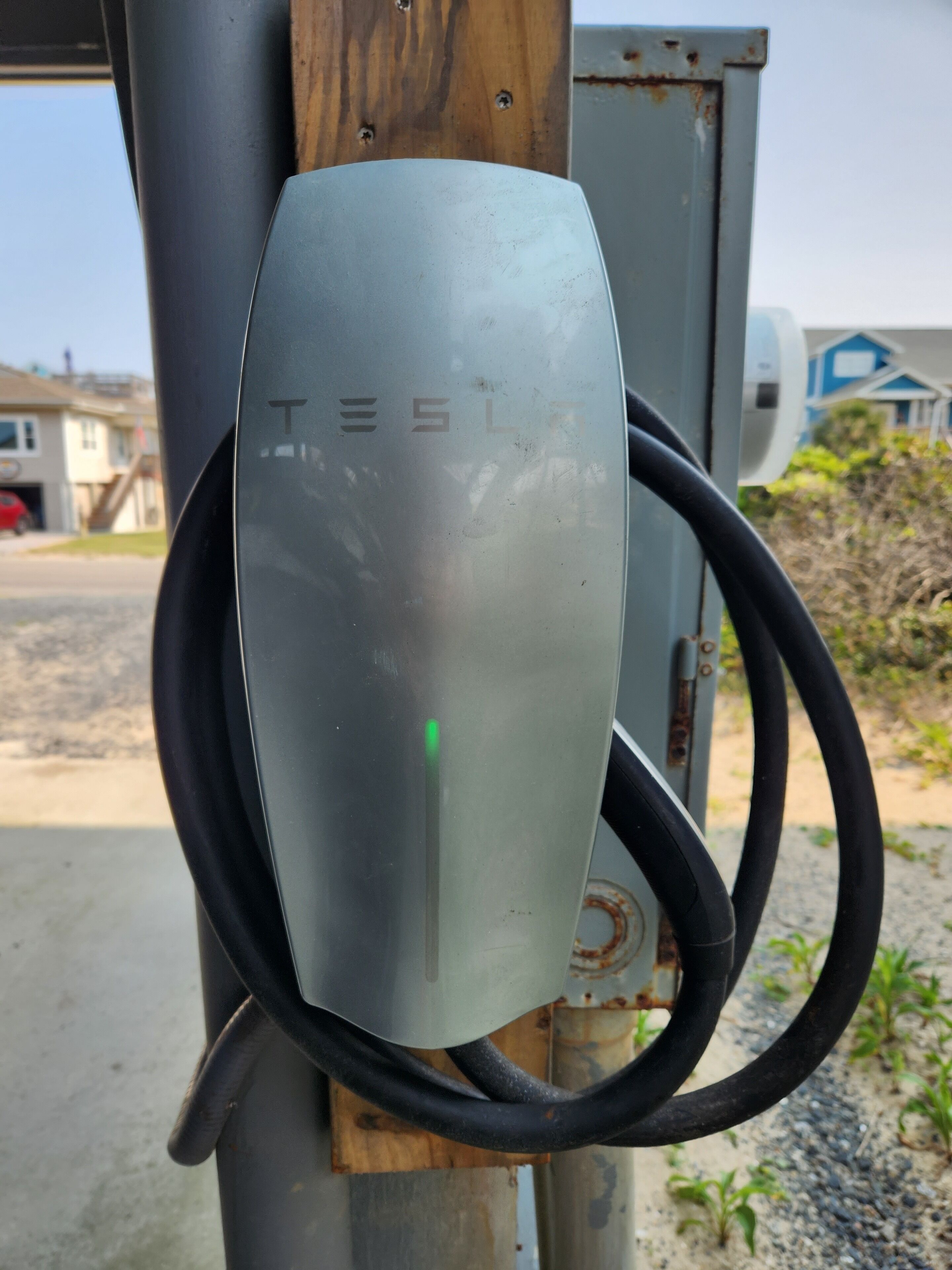 Une borne de recharge pour véhicules électriques Tesla, avec un câble branché.