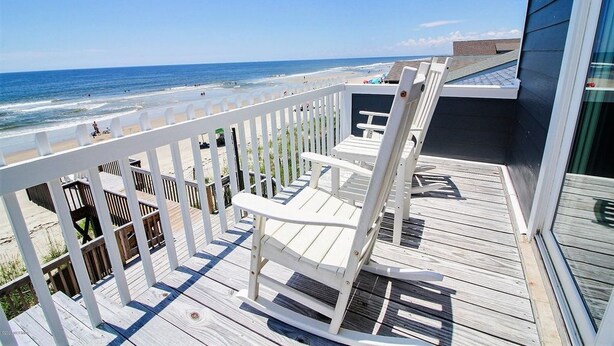 A wooden deck with a white railing overlooking a beach. - Tropic like Its Hot Oak Island Oceanfront House, Tropic Like Its Hot Oak Island- Beach Front (Oak Island)