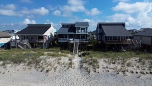 A beachfront property with multiple houses, some elevated on stilts, and a sandy beach in the foreground. - Tropic like Its Hot Oak Island Oceanfront House, Tropic Like Its Hot Oak Island- Beach Front (Oak Island)