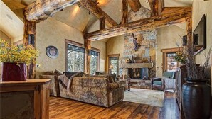 A rustic interior with exposed wooden beams, a stone fireplace, and a cozy seating area. - Rustic-elegance wrapped in custom mountain luxury, steps from Baldy Hiking Trail and shuttle stop (Breckenridge)
