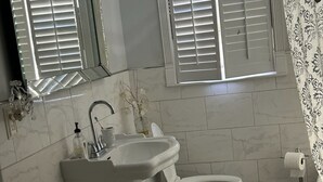 A bathroom with a sink, toilet, and a window with blinds.