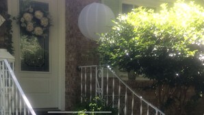 A brick house with a white door, a white railing, and a wreath on the door.