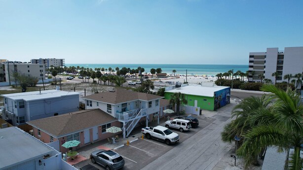 A coastal area with a parking lot, buildings, and a beach in the background.