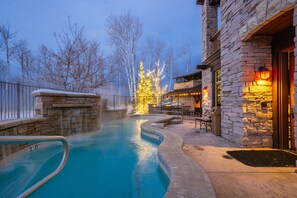 A stone building with a pool, a covered seating area, and a Christmas tree with lights. - Silver Strike by Luxury Mountain Destina (Park City)